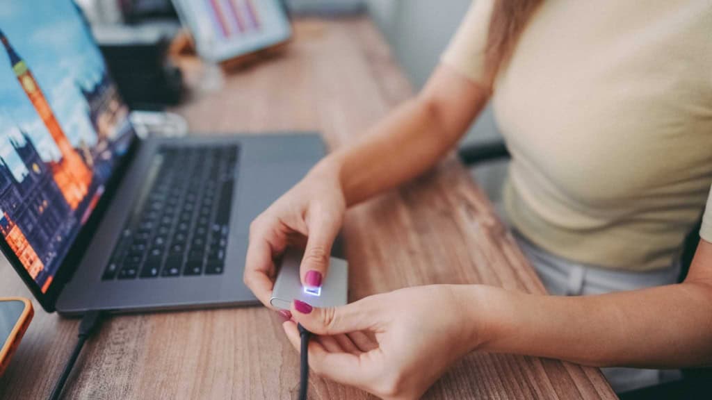 a woman using a portable SSD to backup her work, having read essential digital nomad tips 
