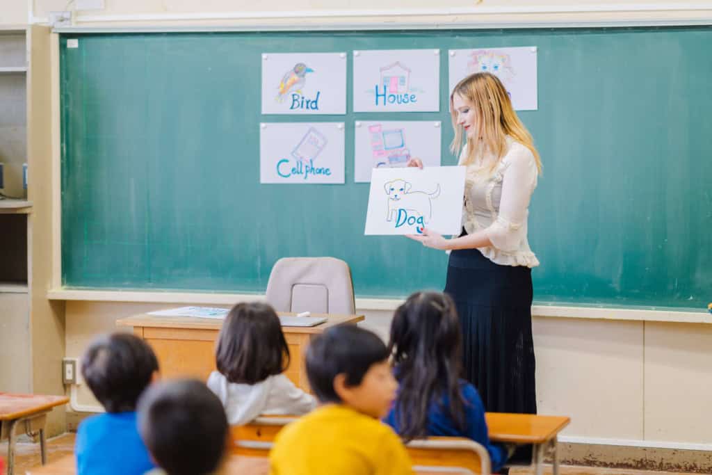 a teacher teaching children with visual aids of words and pictures, fostering language development and early literacy skills in a classroom setting, showing one of the most popular overseas jobs for expats