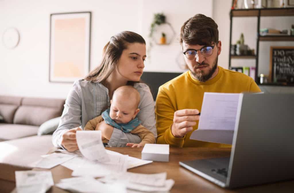 A young family with a baby reviews insurance documents at their dining table, planning international health coverage while considering where should I move, highlighting the importance of global insurance solutions for families living abroad