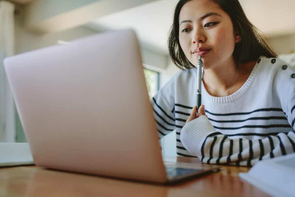 Alt text: Young woman working on a laptop, considering international health insurance options, emphasizing global coverage and accessibility for international citizens.