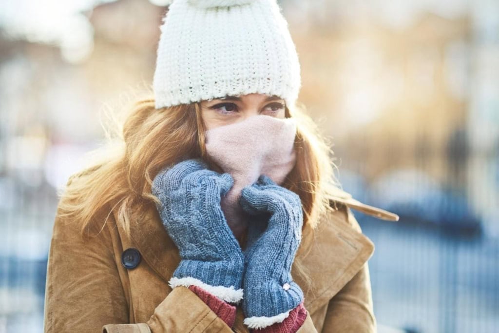 a woman wrapped up warm in a snowy city, protecting herself after reading our expert skin care tips for living abroad
