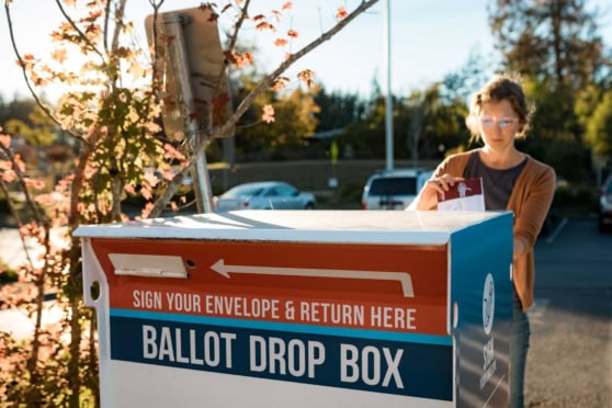 a woman woman deposits absentee mail-in voter ballot