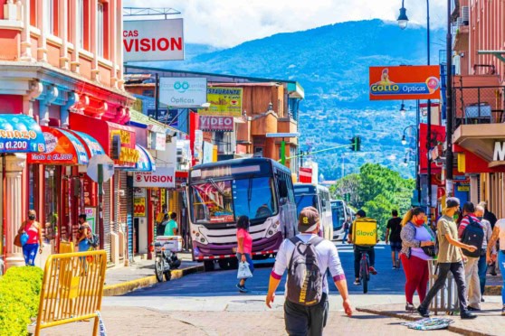 Colorful buses in busy traffic on a street in San José, Costa Rica, illustrating daily life and the cost of living in Costa Rica.