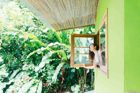 a woman leaning out of a window in a rainforest, indicating an expat moving to Costa Rica from the USA