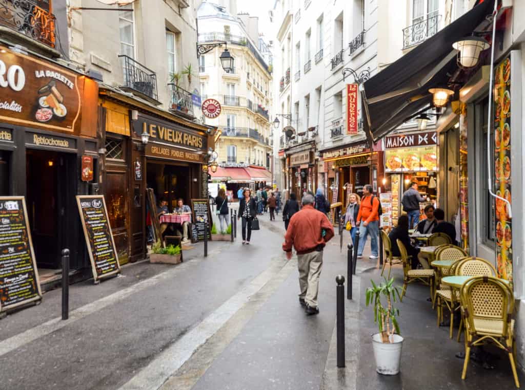 Paris street with cafes, restaurants, and pedestrians enjoying a lively atmosphere. France is an LGBT-friendly country