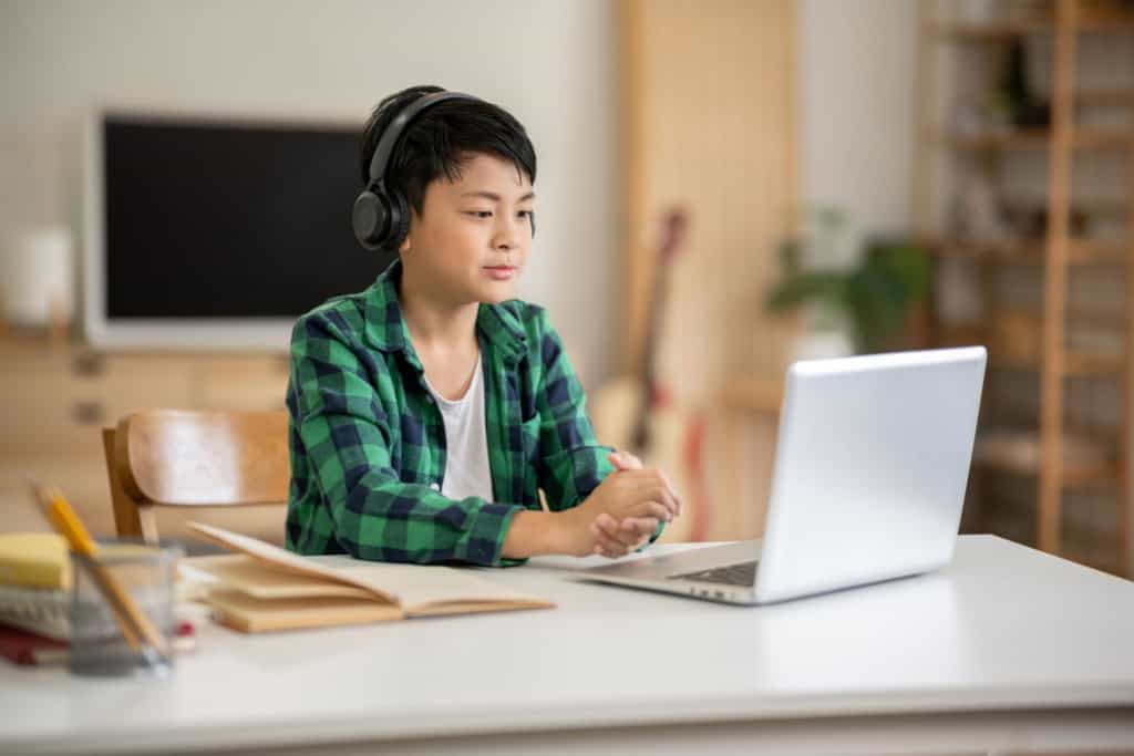 A boy is studying on his laptop at home, showing one option for education abroad 