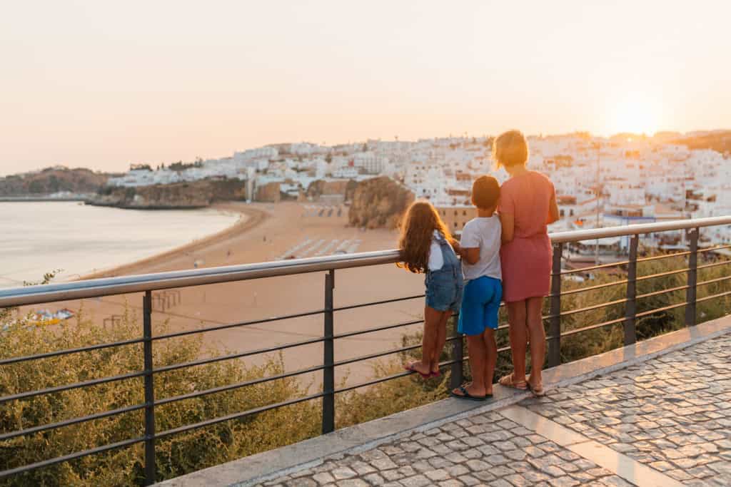 Family enjoying sunset view over a coastal town in Portugal from a scenic overlook. Portugal is an LGBT friendly country
