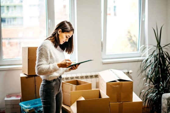 a woman packing her belongings and checking her moving abroad checklist