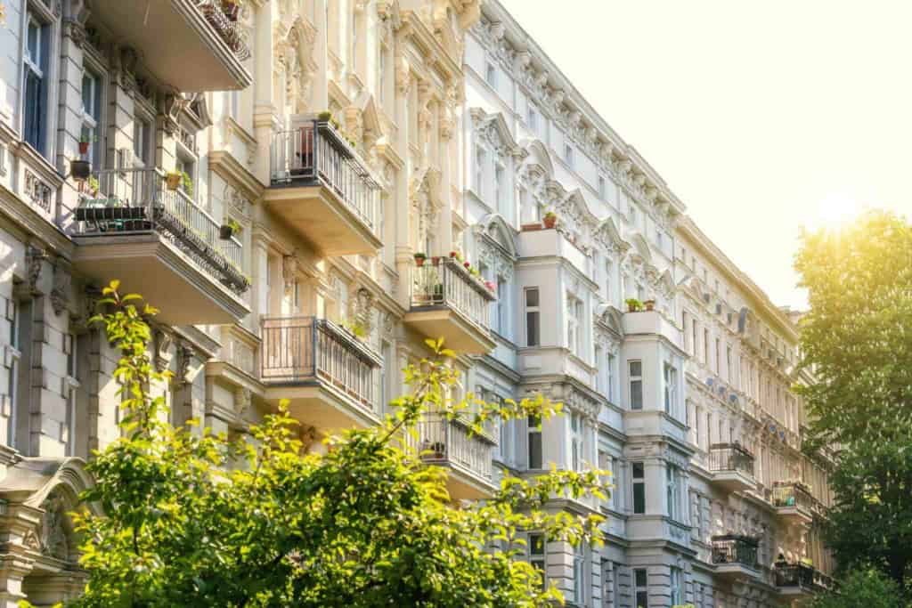 An elegant European apartment building with classic architecture, balconies, and lush greenery, ideal for retirees considering a move to Germany.