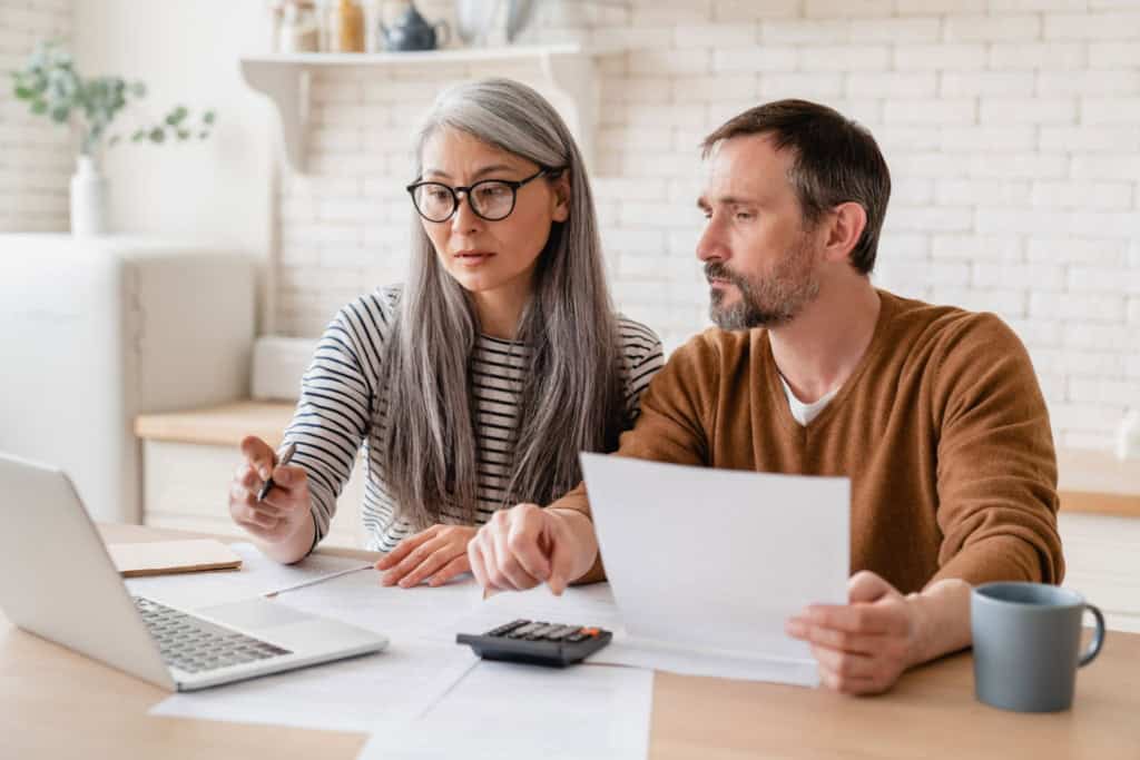 A middle-aged couple looking at funds on a laptop and managing their finances abroad