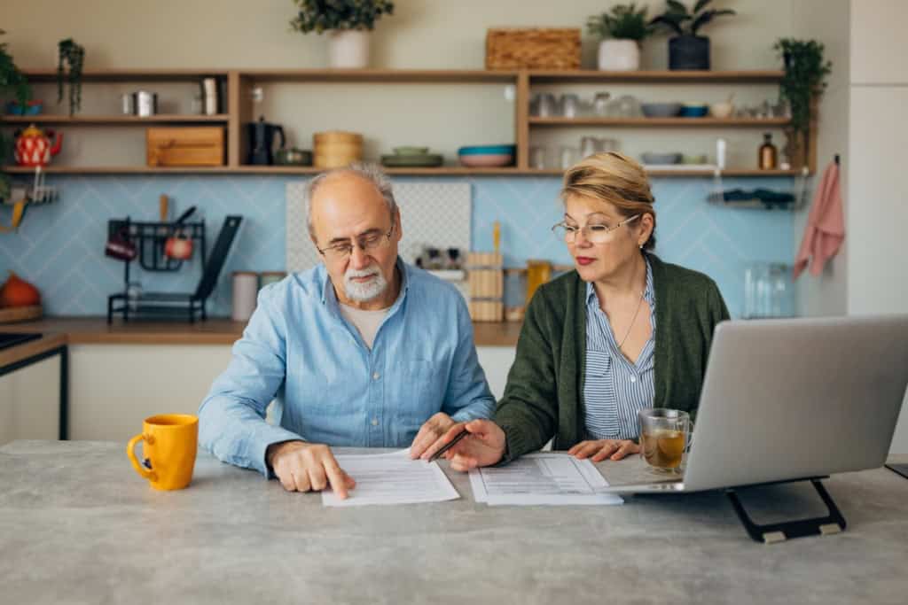 An elderly couple reviewing documents at home, discussing financial plans and insurance options for international insurance.