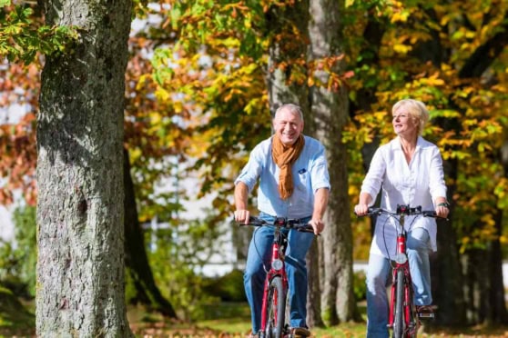 happy couple cycling through a forest after deciding to retire in Germany