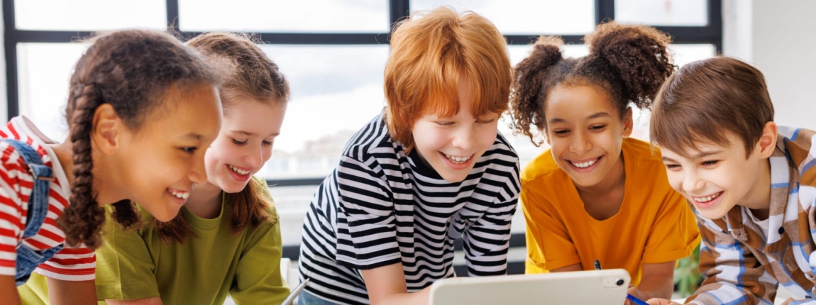 Group of diverse children engaging with a tablet during a classroom activity, promoting education abroad and international student health coverage.