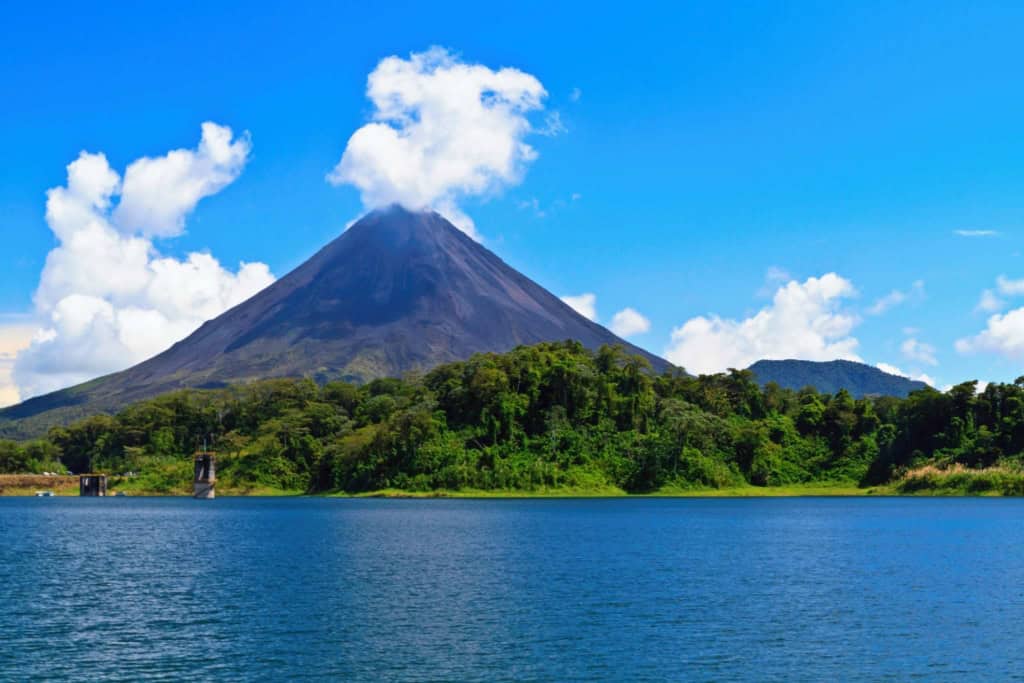 Scenic view of a volcano erupting near a tranquil lake in Costa Rica, highlighting the country's natural beauty and appeal for retirees seeking adventure and relaxation.