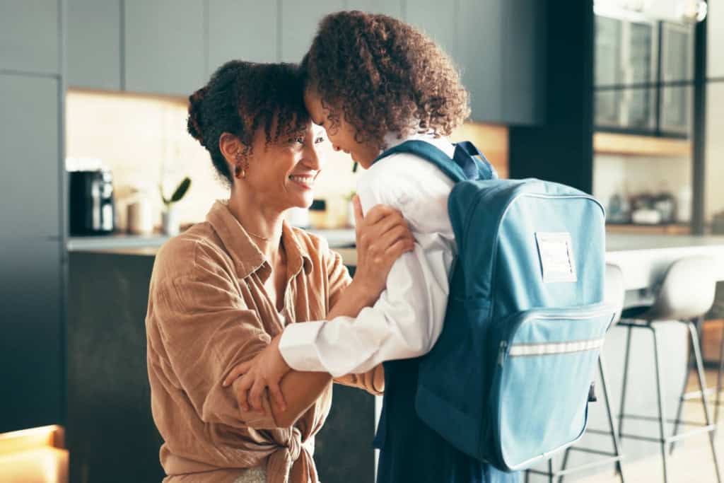 a mother with her child dressed in school uniform, getting ready to go to school