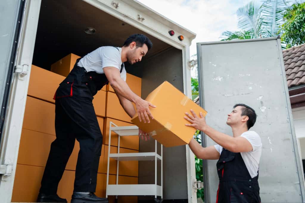 Two movers unloading boxes from a moving truck, preparing for an employee's relocation due to expatriate failure..