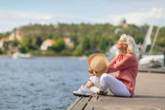 An elderly woman and a young girl sitting by the water in Sweden, enjoying a peaceful moment during retirement.