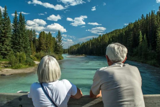 a couple sitting on a hill looking at a beautiful lake in Canada after making the decision to retire in Canada