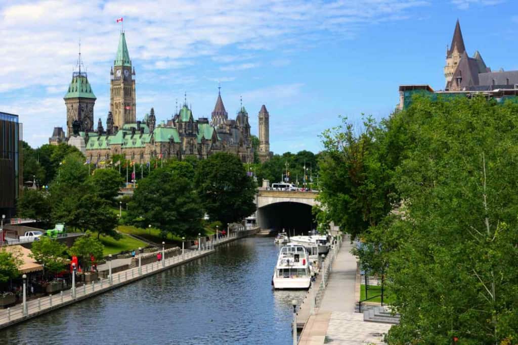 Scenic view of Parliament Hill and Rideau Canal in Ottawa, showcasing historic architecture and lush greenery, ideal for retirees considering Canada's top retirement spots., one of the best places to retire in Canada