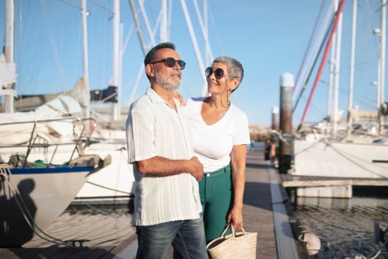 An elderly couple enjoying their retirement by the marina in Portugal, highlighting the importance of international health insurance for retirees living abroad.