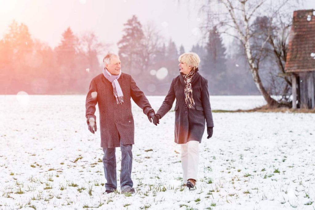A senior couple enjoying a walk outdoors in a snowy landscape during winter in Germany.