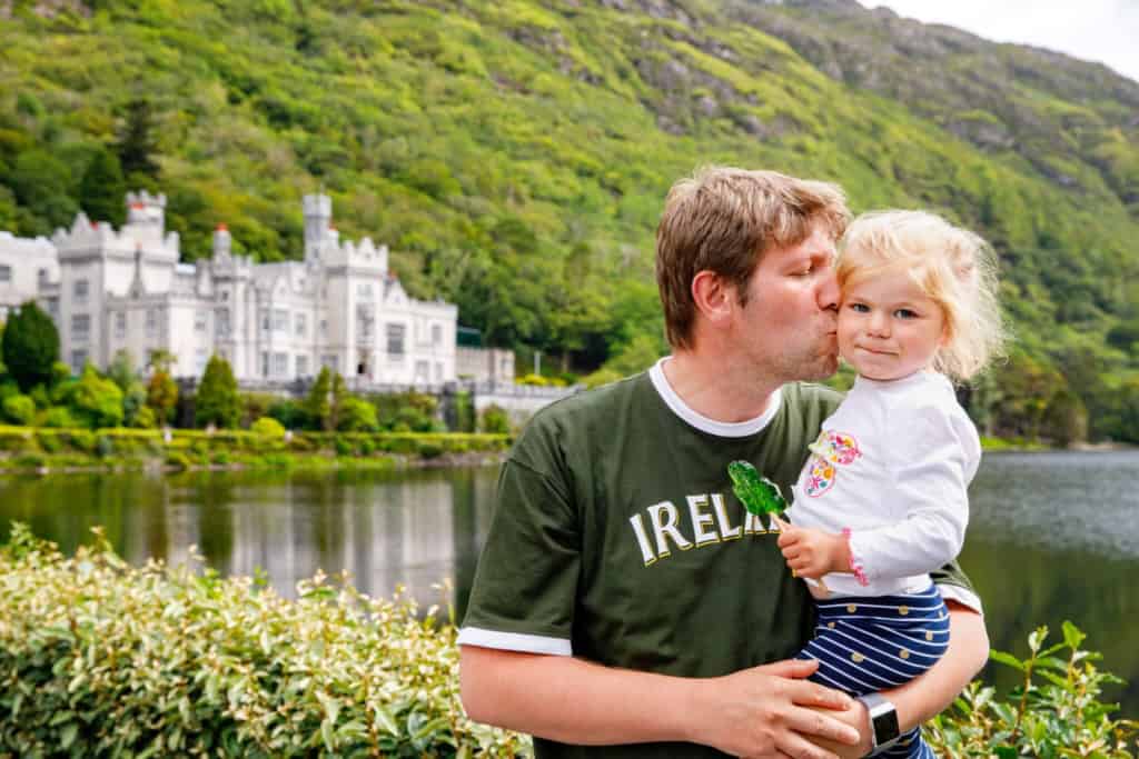 A father and daughter enjoying a scenic outdoor moment near a castle in Ireland, highlighting the beauty of European destinations for expatriates and travelers.