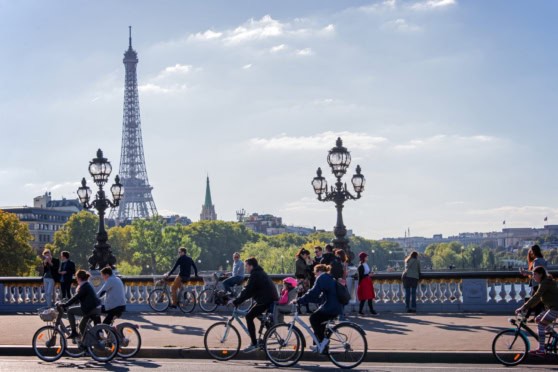Eiffel Tower and Paris skyline with cyclists and pedestrians on a sunny day.