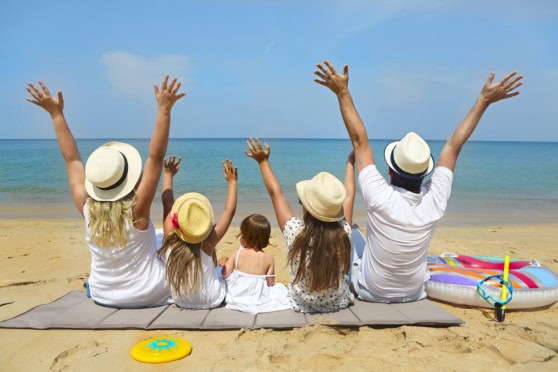 Family relaxing on the beach with kids and parents enjoying sunny weather and ocean views.