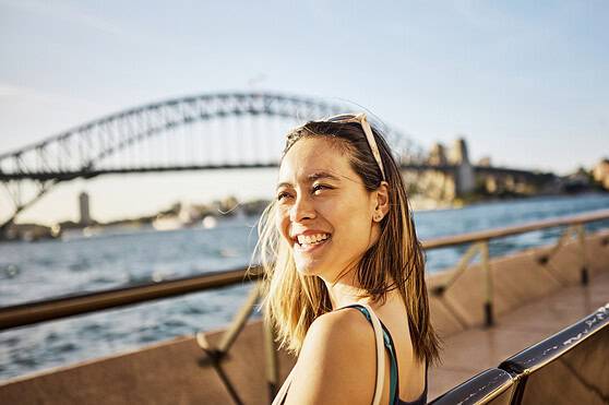 Sydney Harbour Bridge and a smiling woman enjoying the view.
