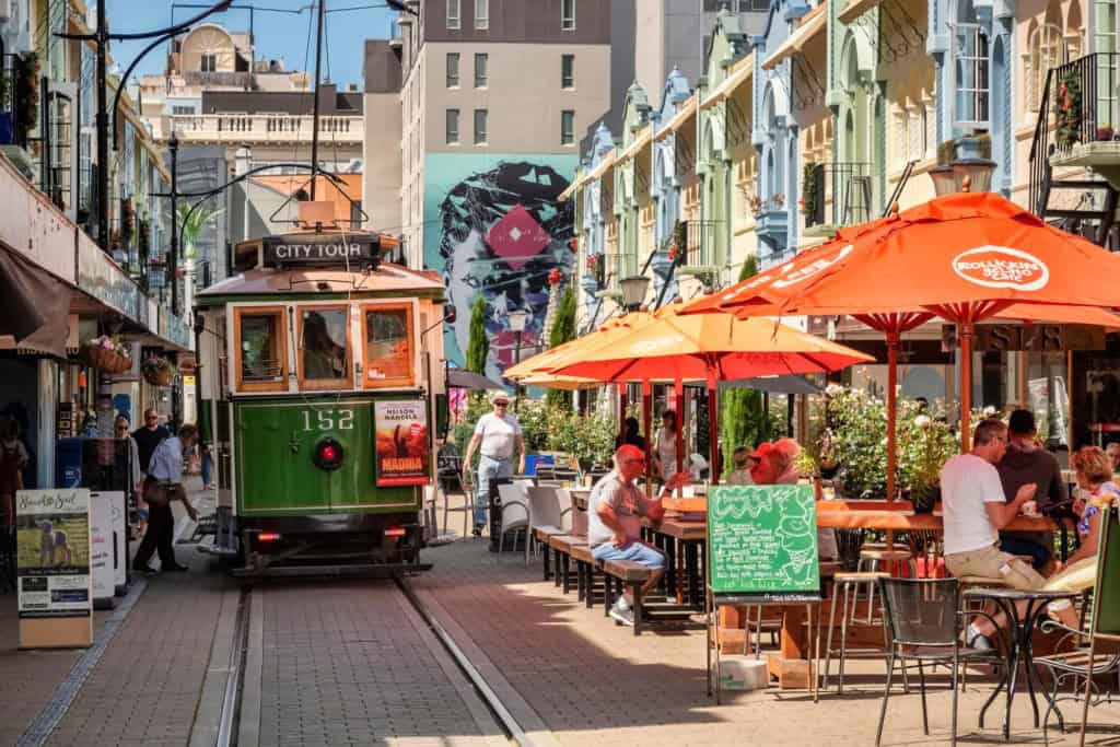 Vibrant street scene in San Francisco with a historic cable car, outdoor dining, and colorful buildings under sunny skies. Perfect for exploring city life and travel safety tips.