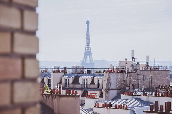 View of Paris rooftops with the Eiffel Tower in the background, showcasing the city's iconic skyline and urban charm. Perfect for illustrating the cost of living in Paris.