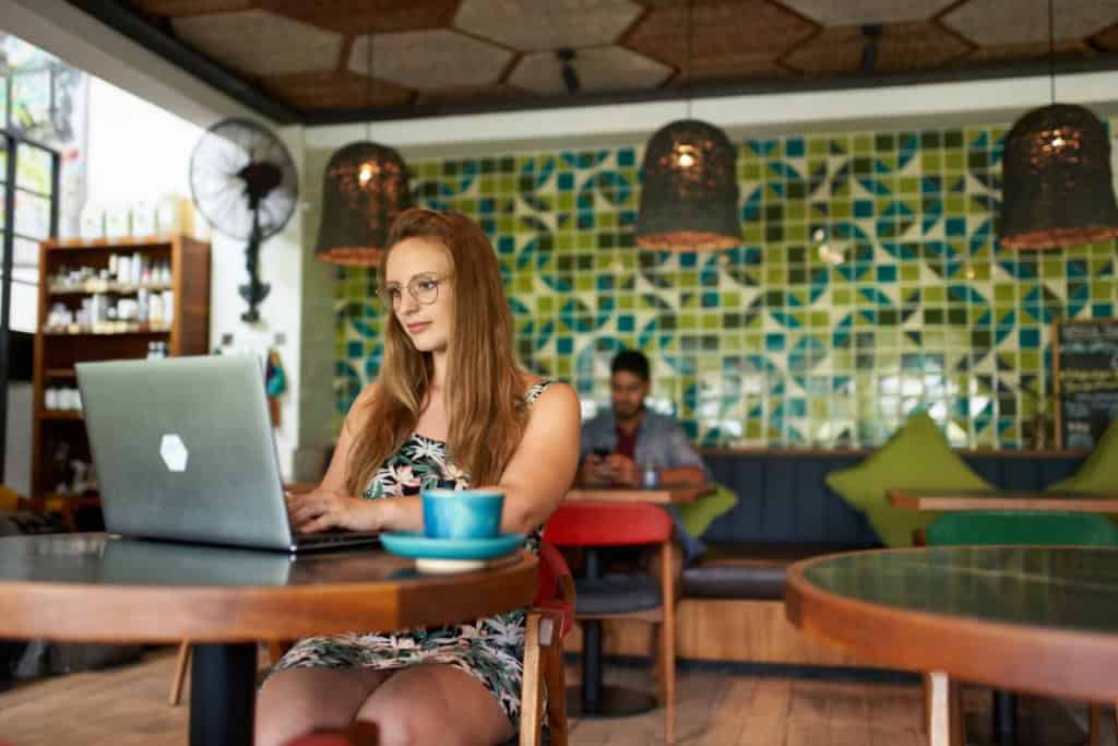 Woman working on a laptop in a cozy cafe, representing international relocation to Canada.