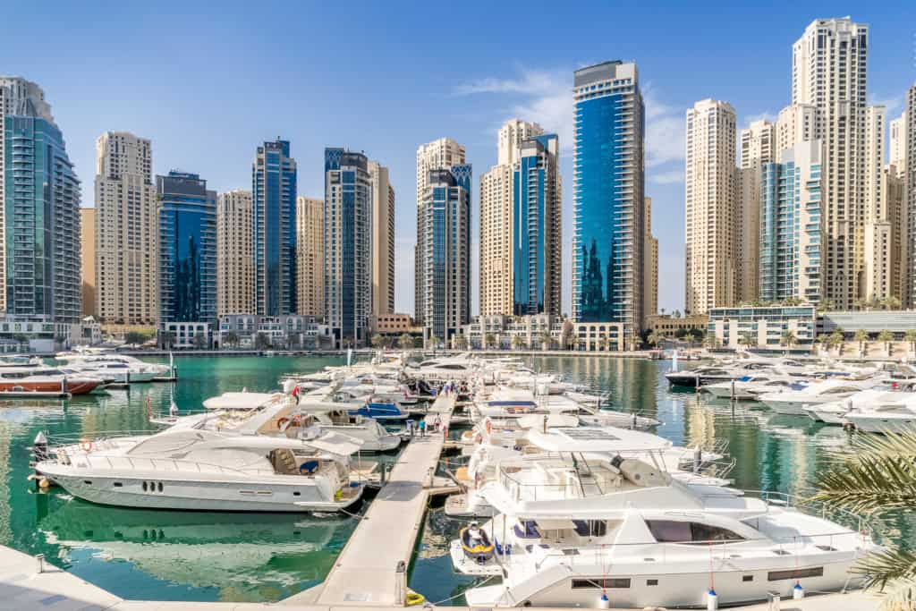 Modern Dubai skyline with luxury yachts docked at the marina, showcasing the vibrant waterfront lifestyle and iconic skyscrapers in the city.