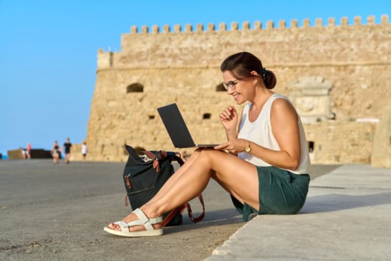 Travel woman using laptop at historic site, Greece.