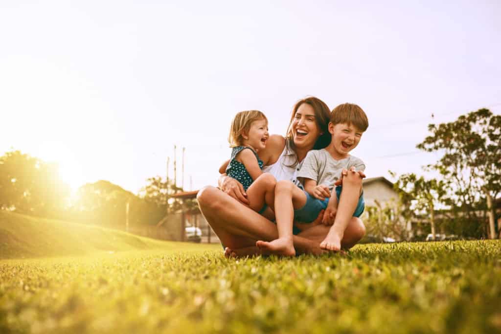 Happy family sitting on the grass outdoors, enjoying the sunshine and embracing the move to Brazil, symbolizing new beginnings and family adventures.