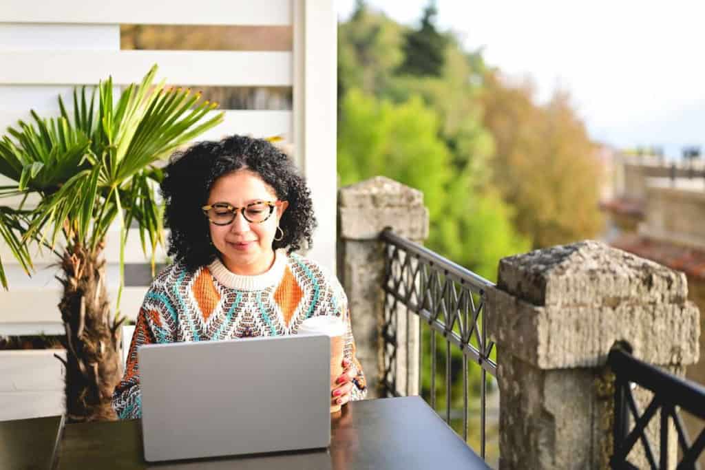Woman working on a laptop outdoors, representing work visa support services in Italy for international citizens.
