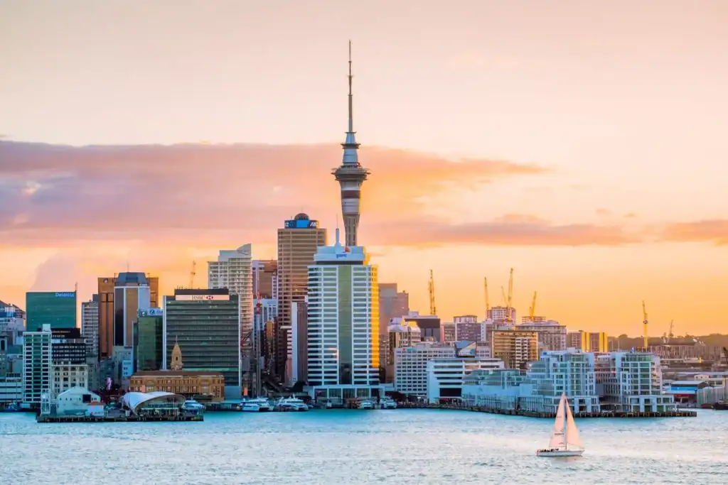 An iconic view of Auckland's skyline at sunset, featuring the Sky Tower and surrounding skyscrapers, highlighting the vibrant urban environment ideal for expats.