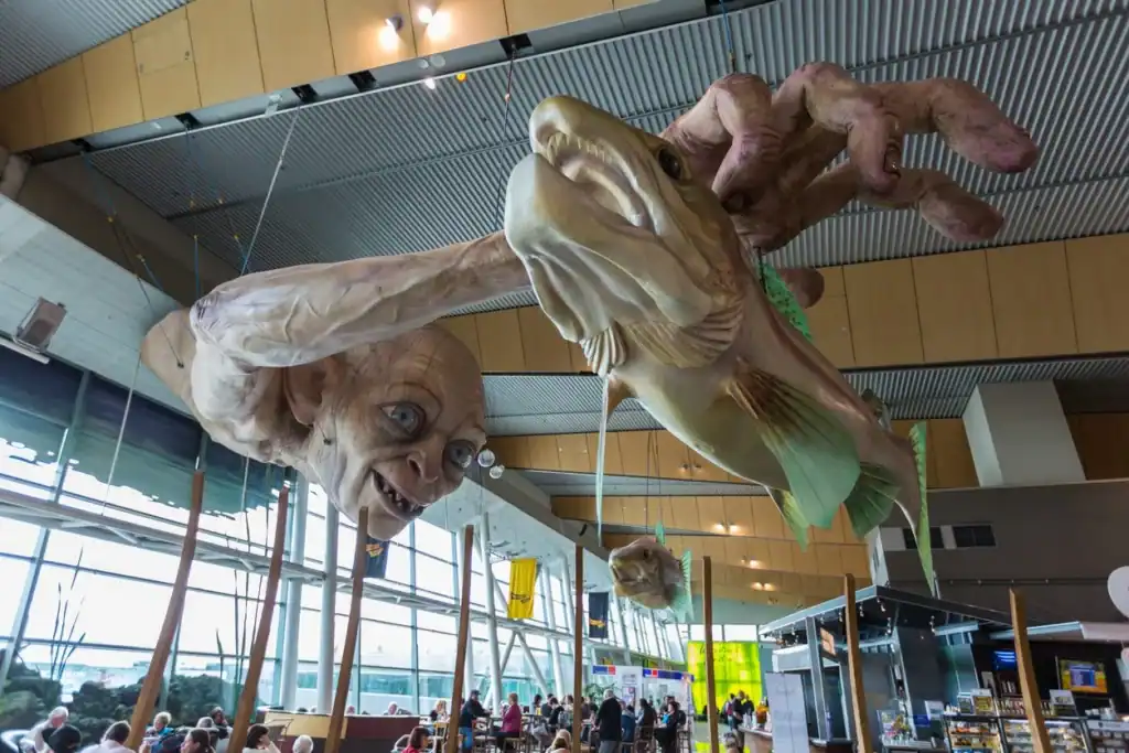 Colorful, oversized animal sculptures hanging from the ceiling in a modern airport terminal.