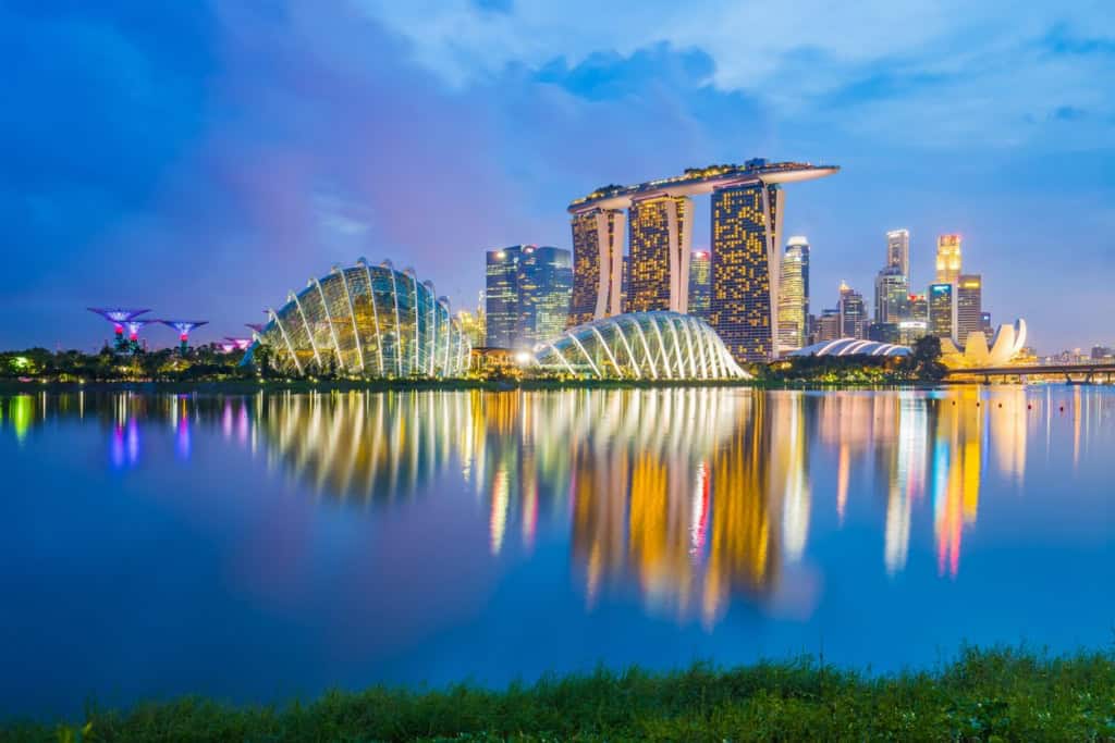 Modern Singapore cityscape featuring iconic Marina Bay Sands hotel and futuristic Gardens by the Bay illuminated at twilight.