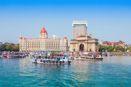 Scenic view of the India riverfront with historic buildings and boats, illustrating the cost of living in India.
