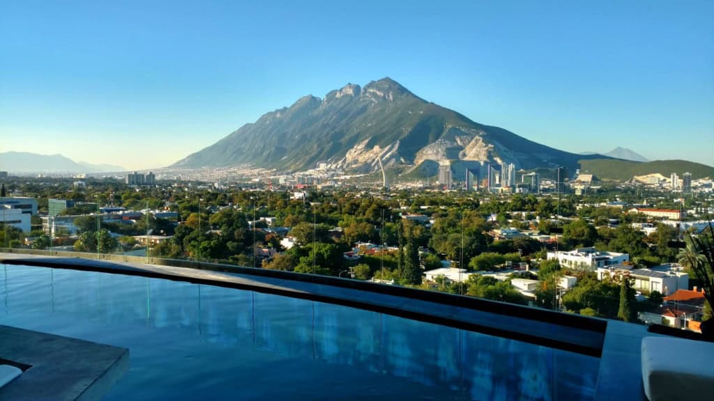 View of Mount Popocatépetl with Mexico City skyline and rooftop pool in the foreground, showcasing the scenic beauty and urban landscape of Mexico.