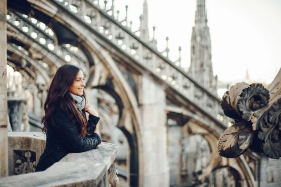 Expat woman enjoying the view of Milan's historic architecture and iconic cathedral, highlighting the experience of living abroad in Italy.