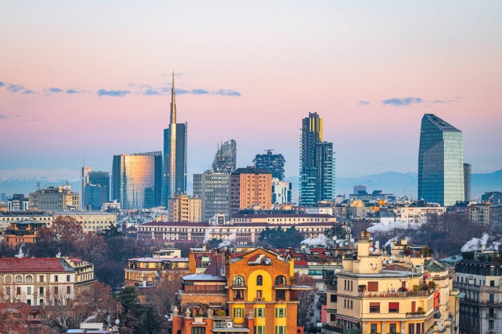 Panoramic view of Milan's city skyline featuring modern skyscrapers and historic buildings during sunset, a city with one of the highest cost of living in Italy
