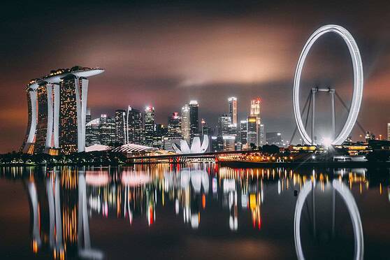 Singapore skyline with Marina Bay Sands hotel and the Singapore Flyer Ferris wheel illuminated at night.