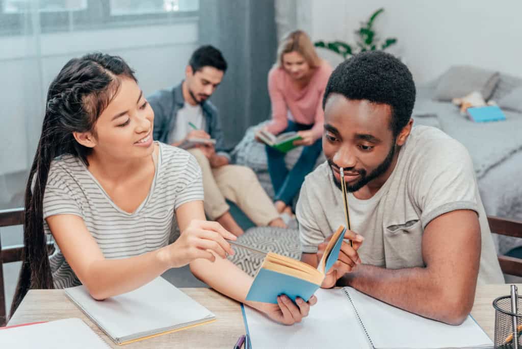 Diverse group of young adults studying together, preparing for international relocation, with a focus on moving from the US to France.