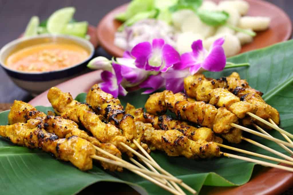 Delicious grilled chicken satay skewers served with spicy peanut sauce and fresh vegetables, perfect for a flavorful Indonesian meal.
