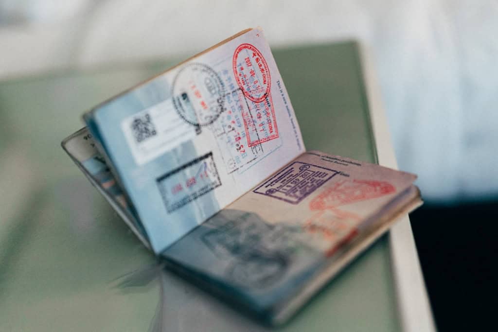 An open passport displaying multiple visas and entry stamps, symbolizing international travel documentation and the process of obtaining Canadian work visas.