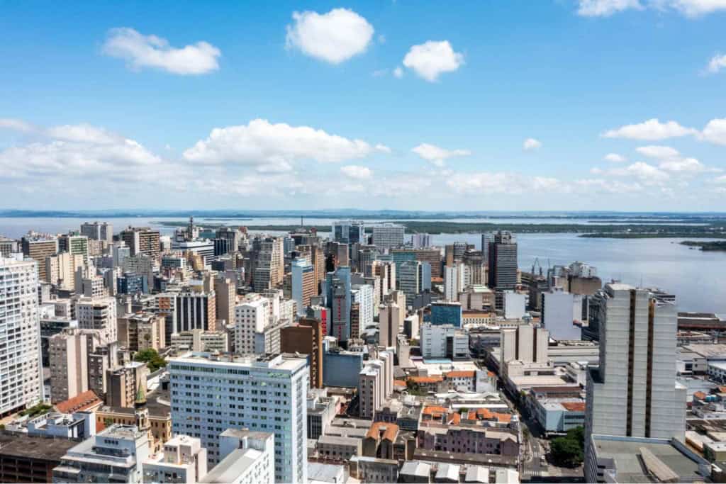 A panoramic view of a bustling Brazilian city skyline with high-rise buildings, a river, and a partly cloudy sky, illustrating urban life and scenic beauty in Brazil.