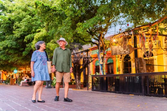 An elderly couple enjoying a stroll in a vibrant Mexican town, highlighting the appeal of retiring in Mexico.