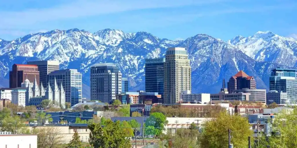 Scenic view of U.S. city skyline with snow-capped mountains in the background, illustrating the cost of living in the United States.